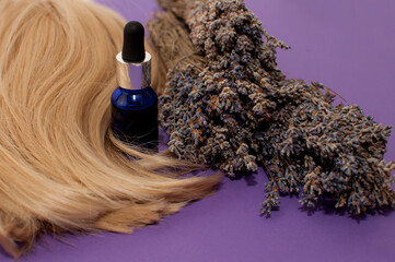 a blue bottle of oil, bouquets of dried lavender and blonde hair on a purple background
