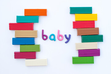 the word baby is made of multicolored plasticine with bars of plasticine around the edges on a white background