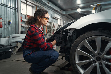 Fototapeta na wymiar Woman car mechanic repairing vehicle in garage