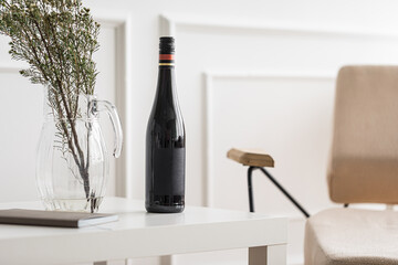 Bottle of wine and vase on white coffee table