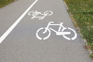 Bicycle lane with white sign painted on asphalt near sidewalk