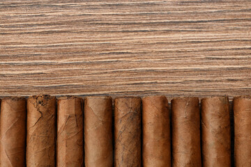 Cigars wrapped in tobacco leaves on wooden table, flat lay. Space for text