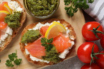 Delicious bruschettas with cream cheese, salmon and pesto sauce on light grey table, top view