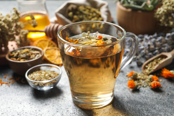 Freshly brewed tea and dried herbs on grey table, closeup