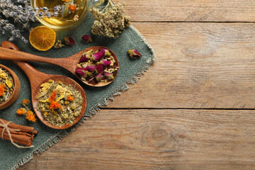 Mix of dried herbs and tea on wooden table, flat lay. Space for text
