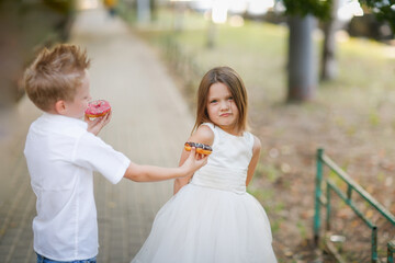boy child treats harmful offended girl with donuts, asks for forgiveness, wants to make friends. Cute funny romantic couple of kids.