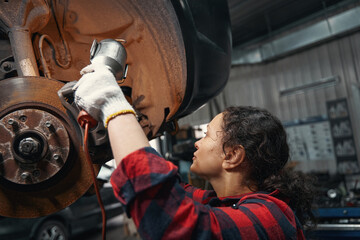 Female auto mechanic repairing car disc in repair service station