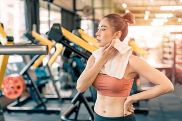 Fototapeta premium Asian girl resting from exercise in the fitness gym and sweat on her face.