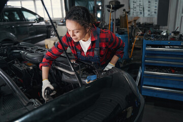 Woman auto mechanic repairing vehicle in car garage