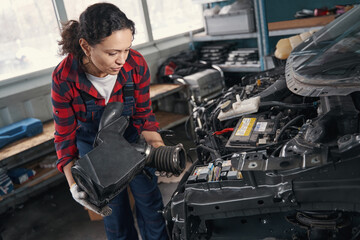 Fototapeta na wymiar Woman automobile mechanic repairing car engine in auto repair shop