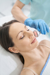 Beautician improving smoothness of facial skin with radiofrequency therapy