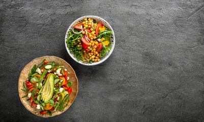 Various summer healthy vegetables salads with avocado, cucumber, radish, bell pepper and tomato on grey background. Healthy food.