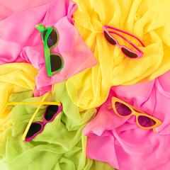 Colorful scarves and sunglasses. Modern fun fashion background. Stylish summer beach accessories. Vacation womens necessities. Flat lay. Vibrant colors.