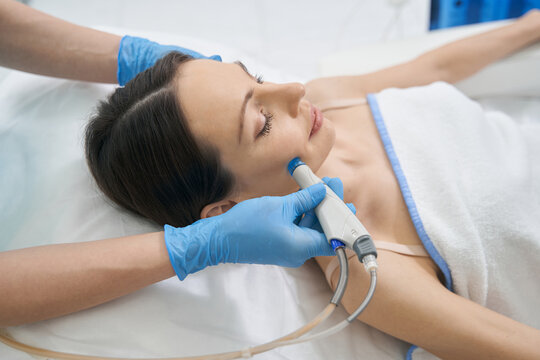 Beauty therapist performing hydrafacial procedure on woman