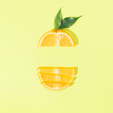 Fresh orange fruit slices with leaves on bright green background. Minimal citrus food concept. Creative summer layout with sunshine shadows and copy space.