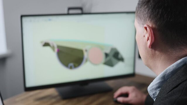 An unrecognizable man develops the design of a part. An engineer works with a 3D model in a design program.
