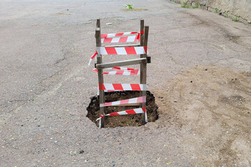 Obraz premium Wooden fence with red warning tape around dug hole.,