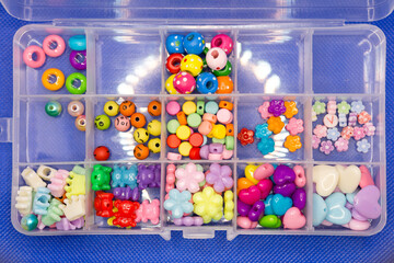Yellow, pink, blue beads of different shapes needlework in plastic box.,