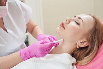 Obraz na płótnie Canvas Calm beautiful woman during the preparing her neck before the beauty procedure