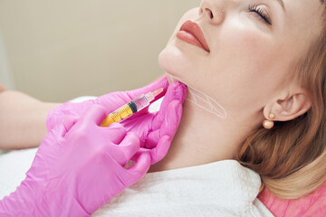 Elegant Caucasian female is getting injection for smoothing of neck wrinkles - obrazy, fototapety, plakaty