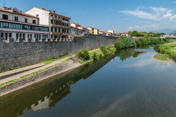 Fototapeta na wymiar The path along the Bisenzio river in the old town of Prato, Italy, on a sunny day