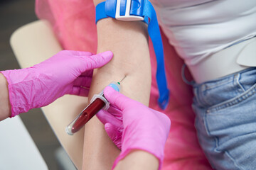 Unrecognized doctor in pink gloves with sample in blood tube in aesthetic clinic