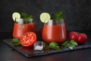 A glass of fresh tomato juice and tomatoes on a wooden background. Natural tomato juice.