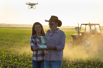 Farmers supervising crop growth and tractor works with drone in corn field