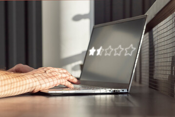 Man using laptop for negative online review. Giving bad feedback in satisfaction survey concept. Sad customer experience. High quality photo