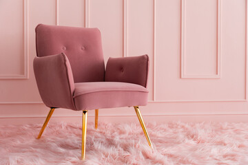 An elegant armchair upholstered in pink velvet, standing on a fluffy carpet. Modern luxury interior
