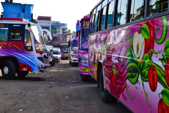 Thalassery, India - January, 2017: Lots of colorful buses at bus station. Pink bus painted with fruits, apples and cherries on side. Typical Indian buses at bus station in Tamil Nadu. KFC in backgroun
