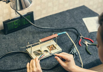 Close - up of female hand and melting wires on the tip of a soldering iron