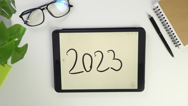 2023 note new year Write text on tablet screen. Electronic pencil for widget notes. Modern reminder on screen. Top view of white desktop in office. Screen glasses. Pocket laptop for modern reminders.