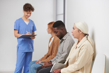 Group of three people sitting in queue waiting for consultation in modern hospital, medical worker...