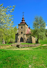 A  stone church in the picturesque landscape in Huta Polanska of the Low Beskids (Beskid Niski) in spring sunny day, Poland - obrazy, fototapety, plakaty