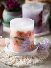 Handmade candles of a unique design, with different flowers, dry leaves on a light background. Candles made from organic wax, paraffin wax. Relaxation atmosphere. Luxurious lifestyle.