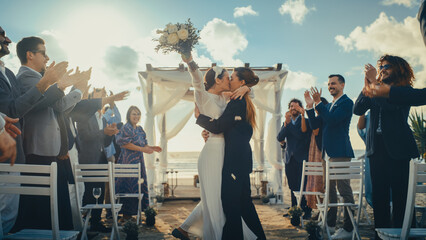 Attractive Female Queer Couple Walking Up the Aisle at Outdoors Wedding Ceremony Near Ocean. Two...