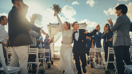 Attractive Female Queer Couple Walking Up the Aisle at Outdoors Wedding Ceremony Near Ocean. Two...