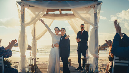 Beautiful Female Queer Couple Exchange Rings and Kiss at Outdoors Wedding Ceremony Near a Sea. Two...