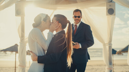 Beautiful Female Queer Couple Exchange Rings and Kiss at Outdoors Wedding Ceremony Near Ocean. Two...