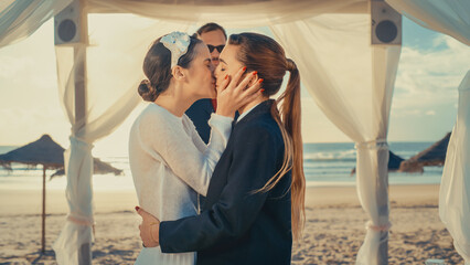 Beautiful Female Queer Couple Exchange Rings and Kiss at Outdoors Wedding Ceremony Near a Sea. Two...