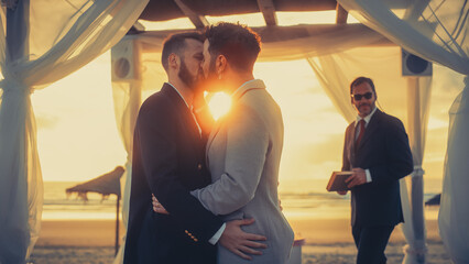 Close Up of Handsome Gay Couple Exchange Rings and Kiss at Outdoors Wedding Ceremony Venue Near the...