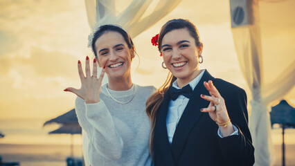 Portrait of a Happy Just Married Beautiful Lesbian Couple Kissing, Showing Off Their Gold Wedding...