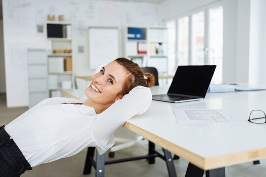 young businesswoman leans at her desk and takes a break