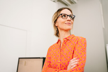 modern woman with glasses stands in office and looks to the side