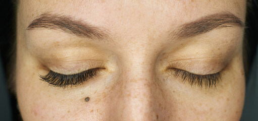 close-up closed female eyes. before and after. eyelash extensions for one eye