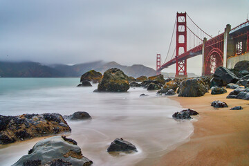 Blurry waves of water hitting sandy and rocky beach southwest of Golden Gate Bridge