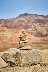 Fototapeta na wymiar Cairn rock stack in front of mountain with colorful layers