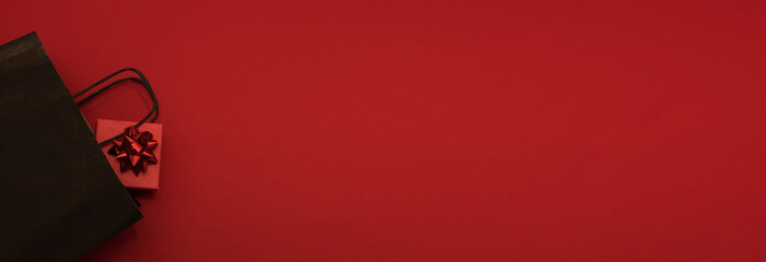 Black Friday, discounts, sales, Christmas shopping on a red background, a place for text, a black gift box with a red bow on a red background, a banner