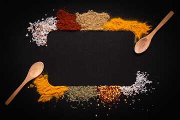 Various spices spoons on black background with copy space top view